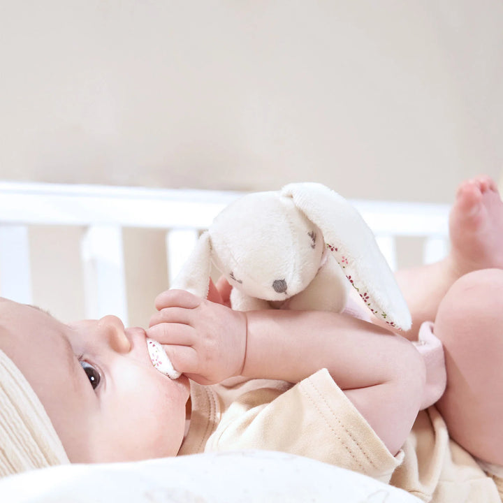 Newborn baby playing with pink baby comforter.