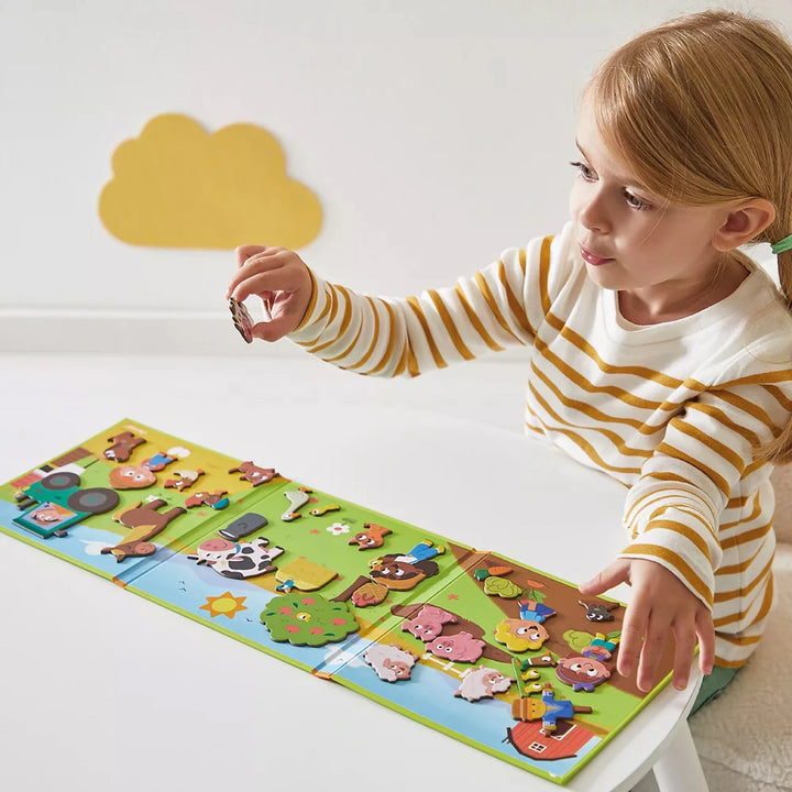 Child playing with Farmyard Fun Magnéti'book Stories set, placing farm animal magnets on a barn scene.