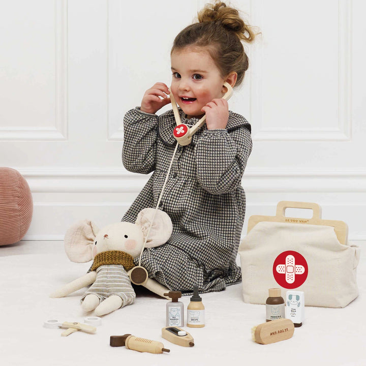 A toddler is playing with the toy vet set.