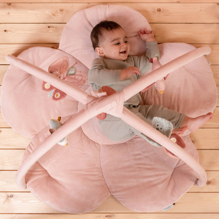 Baby playing on flower-shaped activity playmat.