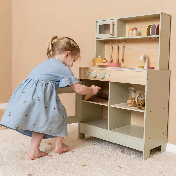 A girl is playing with toy kitchen.