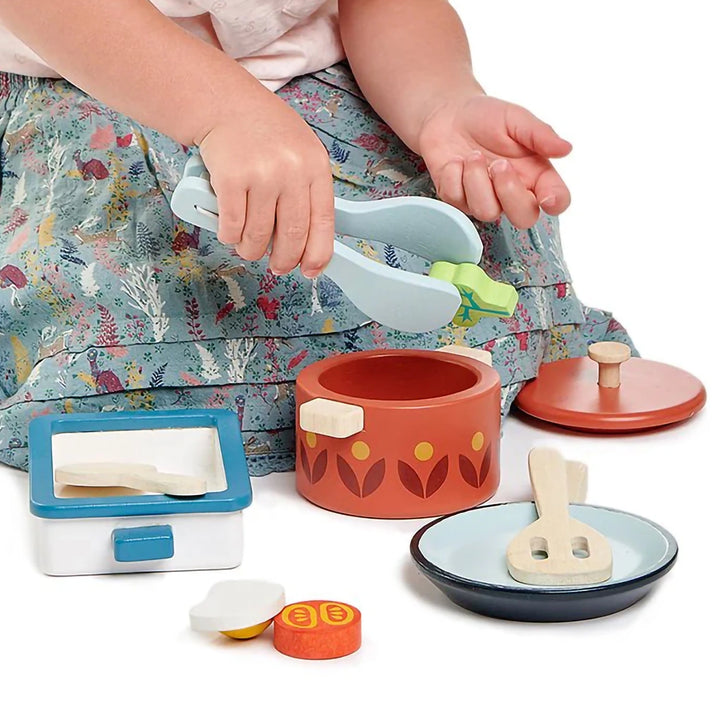 Child playing with Tender Leaf wooden kitchen accessories.