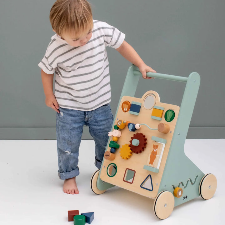 Child playing with a wooden activity walker featuring animal designs