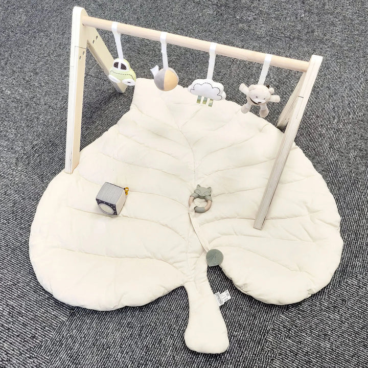 Infant play mat gym with wooden frame and hanging toy.