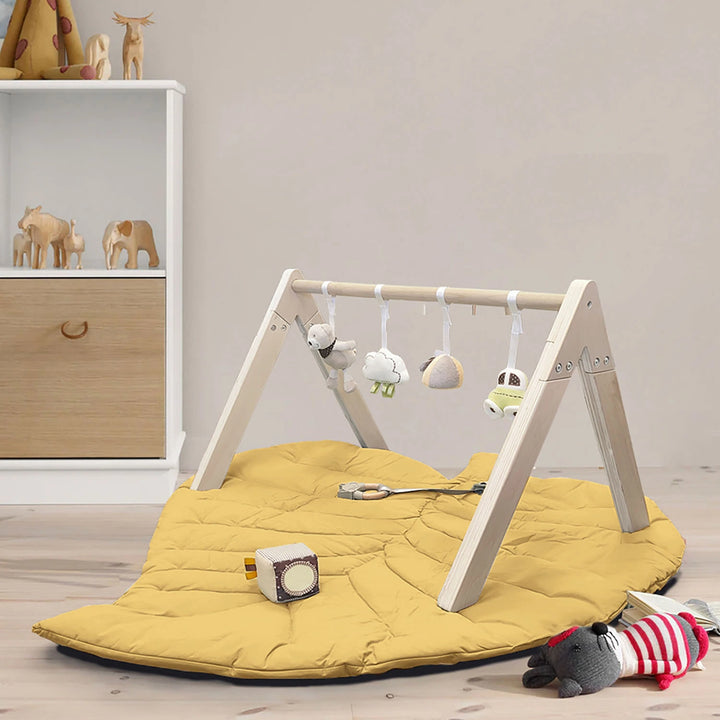 Wooden baby gym with leaf-shaped playmat and sensory toys.