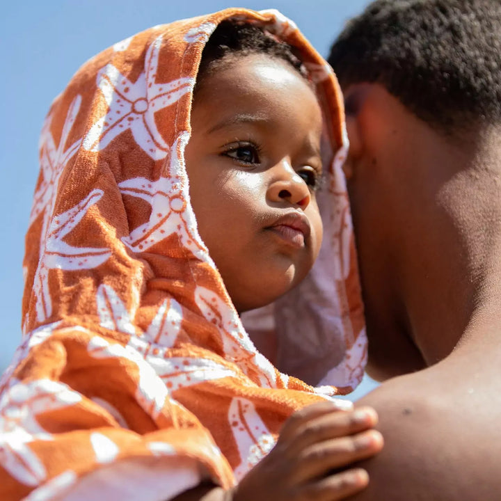 Parent putting the beach poncho on a child - Demonstrating the ease of putting on and taking off the poncho.