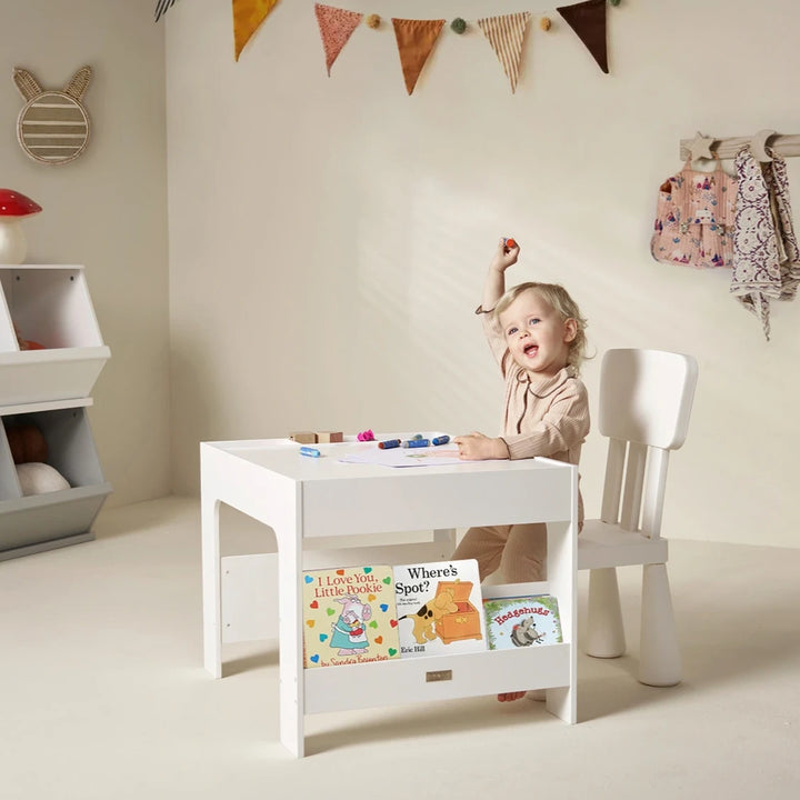 On the wooden activity table that houses the books, a child is drawing.