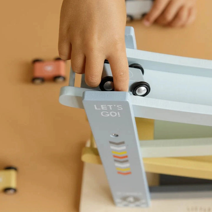 Close-up of four brightly coloured wooden toys lined up at the top of a blue wooden ramp.