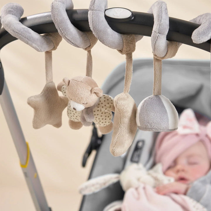 The baby is sleeping in the pram, with a plush spiral activity toy, rattle, squeaky toy, and mirror attached.