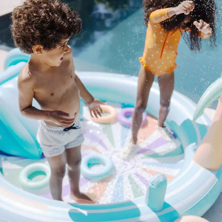 Kids enjoying a splash in the vibrant Rainbow Paddling Pool with its colorful design.