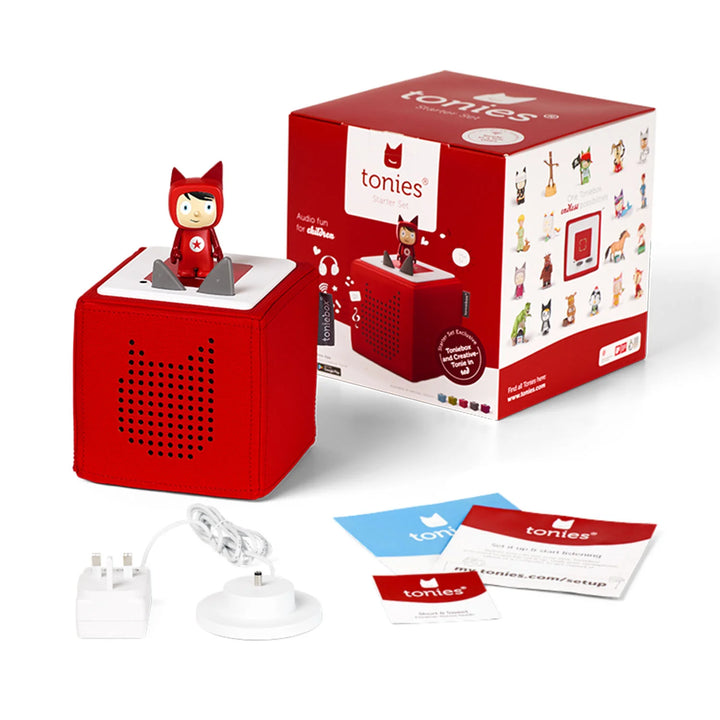 The package includes a red tonie box containing a creative tonie figure, which is placed next to its original box. The set comes with a charging station, user guides, and the Toniebox.