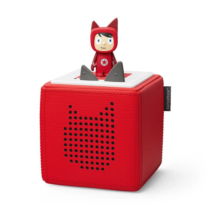 A red tonies starter set with a creative tonie figure on top is designed for children. The Toniebox is a soft, cube-shaped audio player with a small figure standing on top, which activates the device.