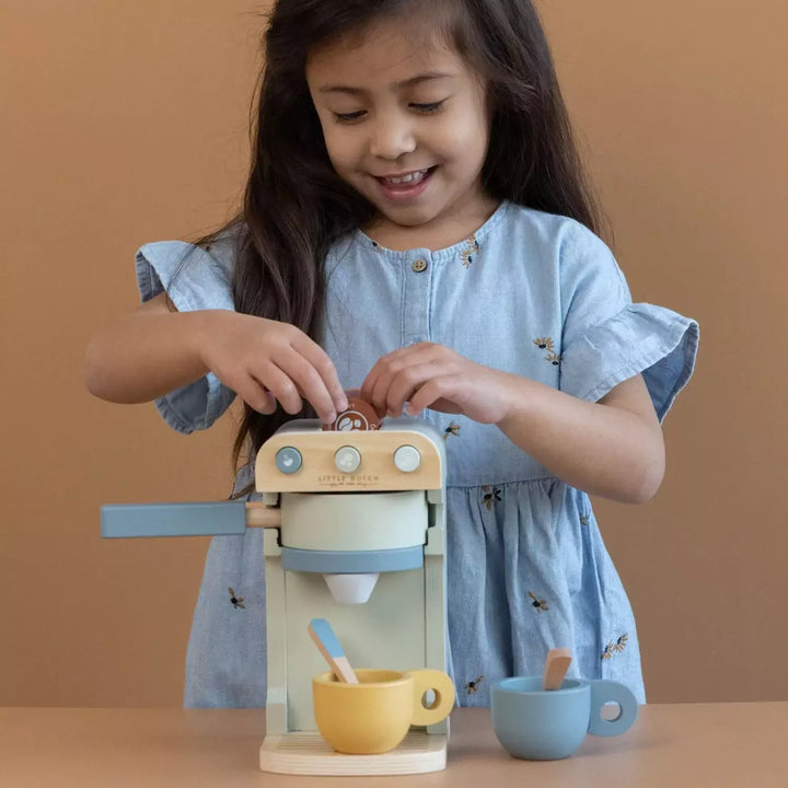 Child's hand placing a coffee pod into the top of a coffee machine.