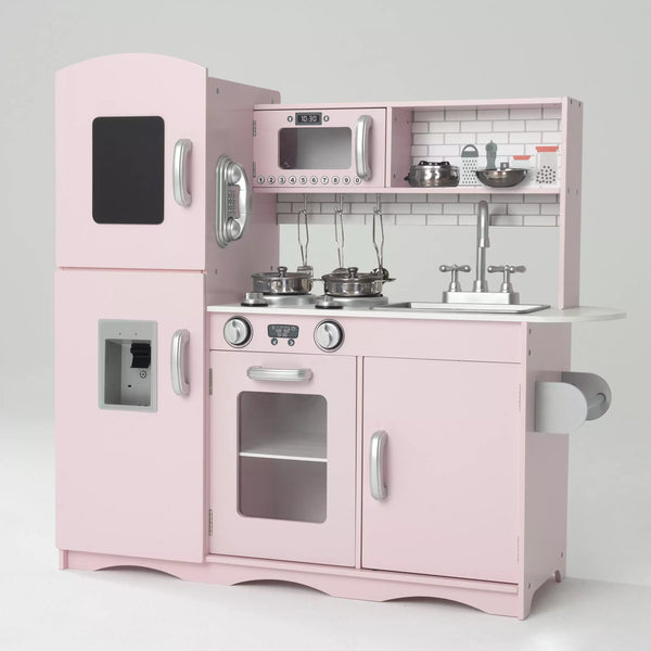 A light pink wooden play kitchen with silver accents has a fridge, freezer, oven, hob, microwave, sink, cabinets, shelves, and storage space.